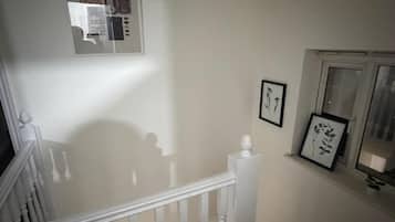 A staircase with a white railing, a wall-mounted picture frame, and a window with a view.