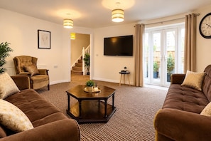A living room with a sofa set, a coffee table, a TV, and a staircase leading to a balcony. - Manchester Spacious 4-bed House, Sleeps 6 (Manchester)