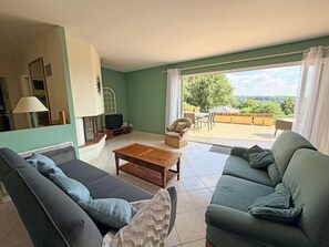 A living room with a sofa, a coffee table, and a television. There is a balcony with outdoor seating. - La Colline Haute, private pool (SAGELAT)