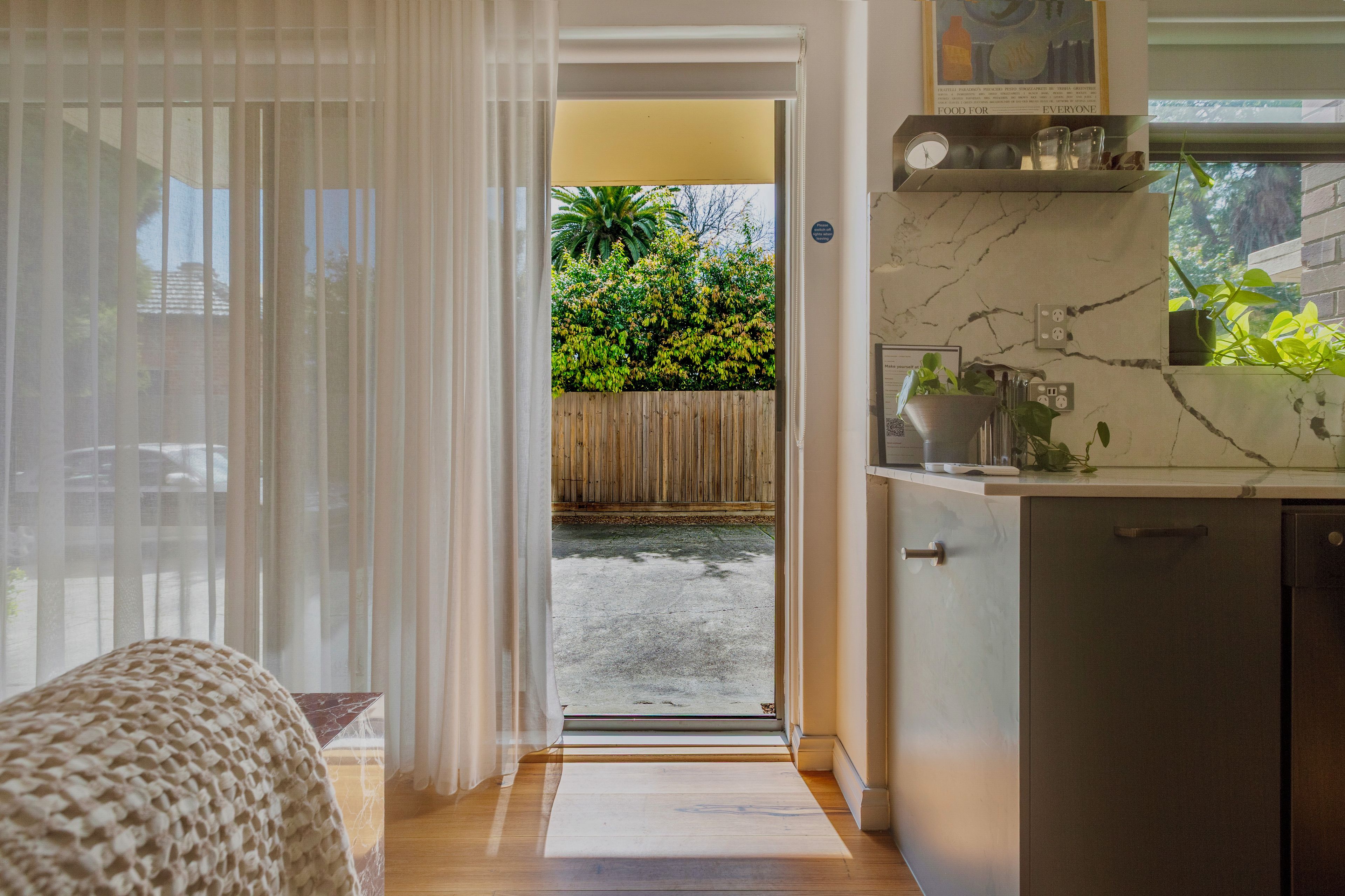 A kitchen with a wooden countertop, a sink, and a window with a view of a garden.