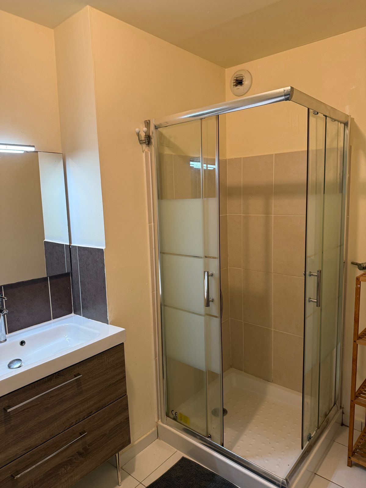 A bathroom with a glass-enclosed shower, a white sink, and a wooden vanity.