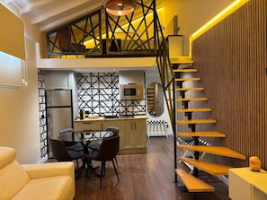 A modern kitchen with a dining area, a staircase, and a living room with a sofa.