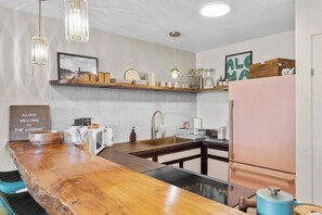 Una cocina moderna con barra de madera, electrodomésticos de acero inoxidable e iluminación colgante.