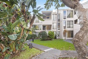 Ein modernes, mehrstöckiges Gebäude mit einem gepflegten Garten und einem Weg zum Eingang.