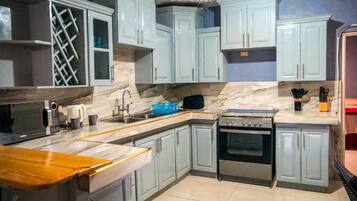 A kitchen with light blue cabinets, a marble countertop, a stove, and a sink.