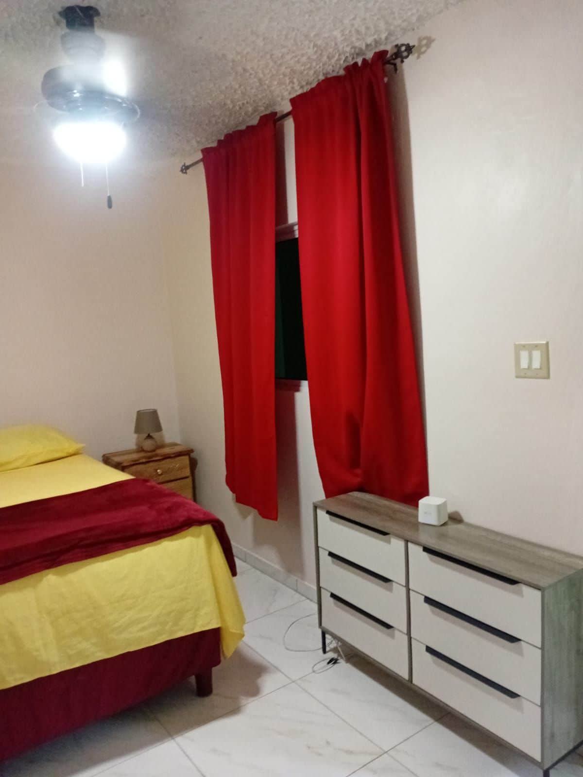 A bedroom with a bed, a nightstand, a dresser, and a ceiling fan.