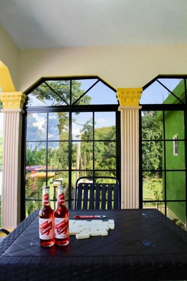 A table with two bottles and several dice, set against a window with a view of greenery.