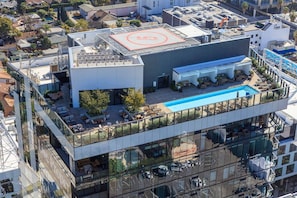 A modern building with a rooftop pool, outdoor seating, and a glass facade. - Skyline Luxe Panoramic Hollywood Views & Rooftop Pool (Los Angeles)