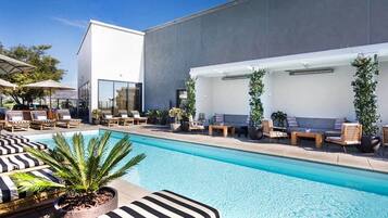 Un área de piscina moderna con sillas de descanso y una piscina grande.
