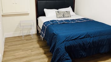 Een slaapkamer met een bed, een raam, een kledingkast en een klein tafeltje.