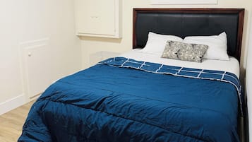 A bedroom with a bed, a window with blinds, a wardrobe, and a radiator.