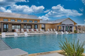 A swimming pool with lounge chairs and a building with large windows and a metal roof. - Firelight Cabin | Loft + 2 Baths | Sleeps 8 (Fredericksburg)