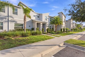 A modern residential area with multi-story houses, well-maintained lawns, and a clear sky. - Champions Gate Escape, Pool, Themed Rooms (Kissimmee)
