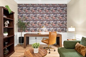 Ein modernes Wohnzimmer mit einem Holztisch, einem Ledersessel, einem grünen Sofa und einer gemusterten Tapete.