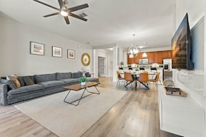 A modern living room with a sofa, coffee table, and dining area with chairs. - Spacious 3BR in Prime Orlando Location (Orlando)