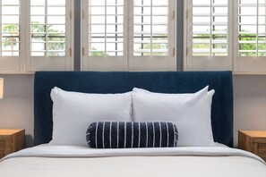 A bed with white bedding and two pillows, a dark blue headboard, and a window with blinds. - 6Bd Scottsdale Resort Style Escape*Heated Pool/Spa (Scottsdale)