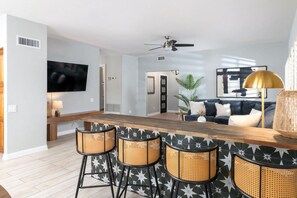A modern kitchen with a bar area, a ceiling fan, and a television mounted on the wall. - 6Bd Scottsdale Resort Style Escape*Heated Pool/Spa (Scottsdale)
