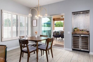 A dining area with a wooden table and chairs, a vase with flowers, and a wine rack against the wall. - 6Bd Scottsdale Resort Style Escape*Heated Pool/Spa (Scottsdale)