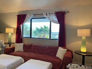 A hotel room with a red sofa, two beds, a window with curtains, and two bedside lamps. - Charm 3bed, centrally located on the foothills, pet friendly, dinning, shopping. (Tucson)
