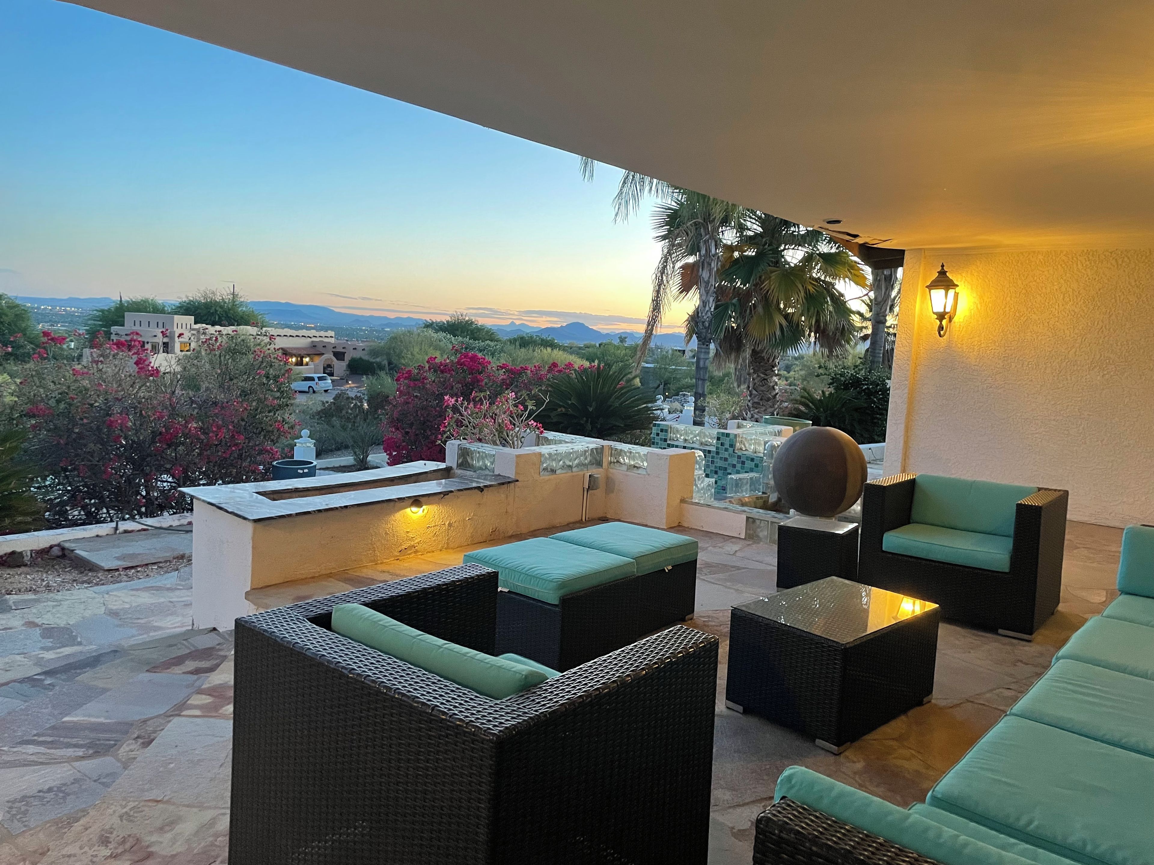 A terrace with wicker furniture, a decorative sphere, and a view of the landscape.
