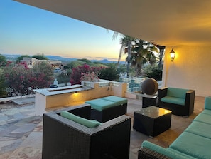 Eine Terrasse mit Korbmöbeln, einer Dekokugel und Blick auf die Landschaft.