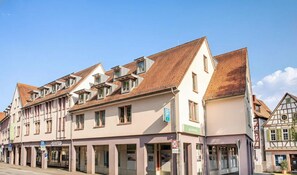 Ein traditionelles europäisches Gebäude mit mehreren Stockwerken, Dachgauben und einer Mischung aus Gewerbe- und Wohnräumen.