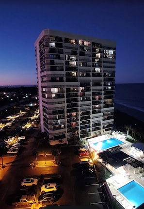 A multi-story hotel with a pool area and parking lot.