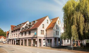 Eine Reihe traditioneller europäischer Gebäude mit einem Parkschild, einer Fußgängerzone und einer Trauerweide.