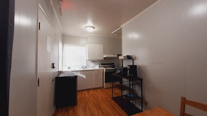 A compact kitchen with a stove, sink, and a coffee maker. - SHERWOOD ARMS MOTEL _ CABIN #7 (Running Springs)