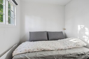 Une chambre avec un lit simple, une fenêtre et une porte.
