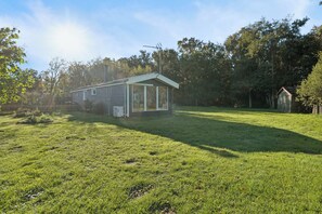 Une petite maison à un seul étage, dotée d’un toit en pente, entourée d’une pelouse bien entretenue et d’arbres.