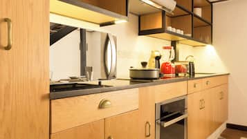 Una cocina moderna con armarios de madera, horno empotrado y refrigerador de acero inoxidable.