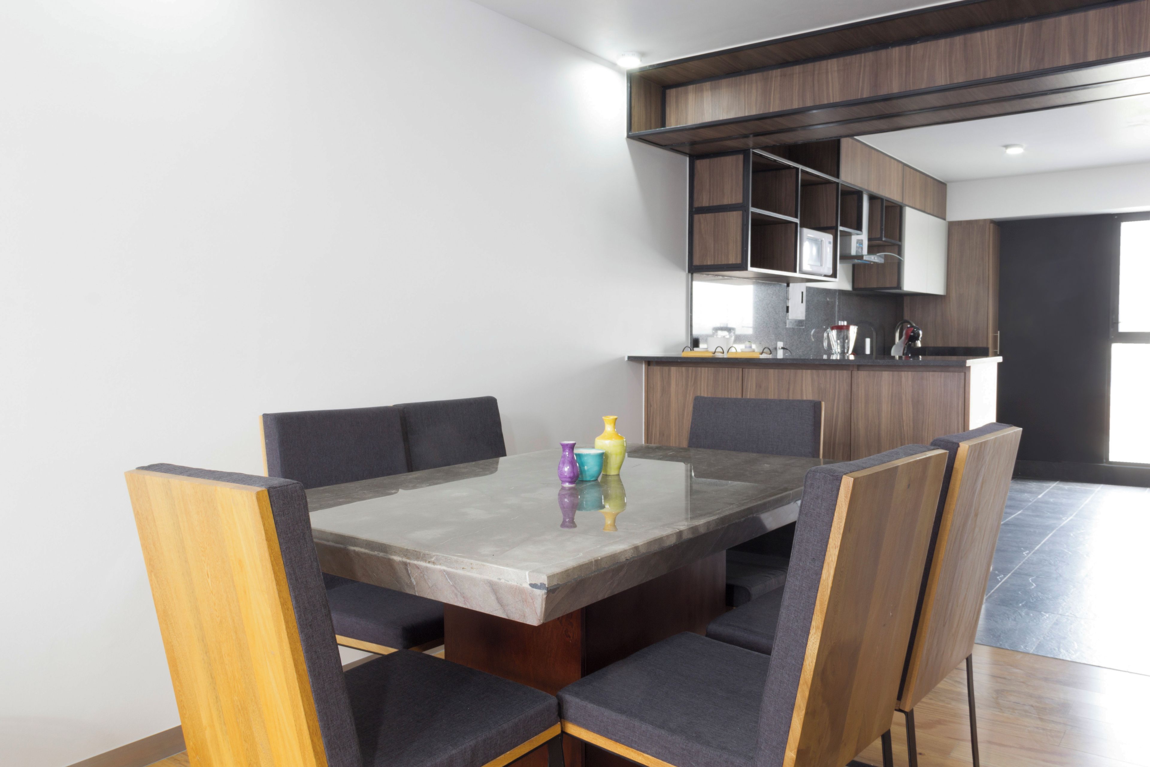 A modern kitchen with built-in appliances and a dining area with a marble table and upholstered chairs.