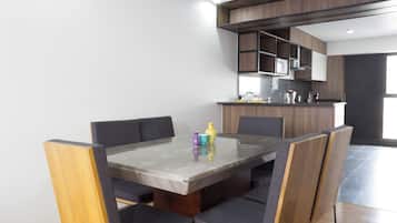 A modern kitchen with built-in appliances and a dining area with a marble table and upholstered chairs.