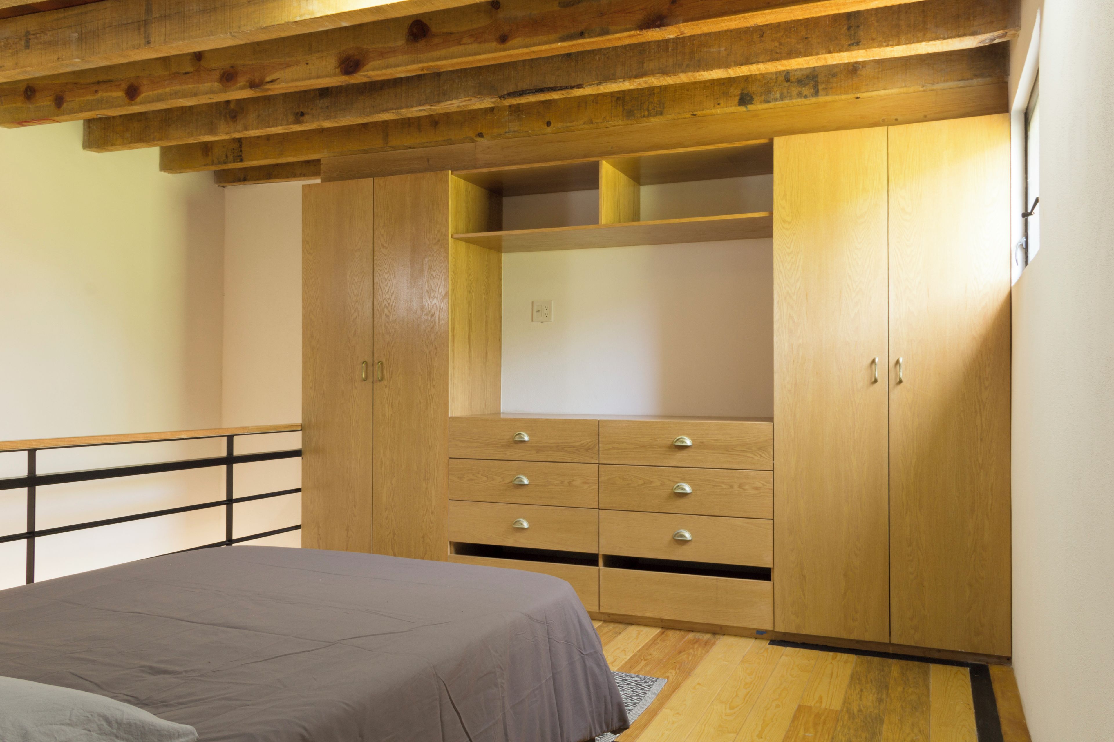 Un dormitorio con cama, armario de madera y un pequeño escritorio.