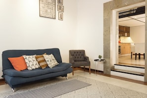 A living room with a blue sofa, a grey armchair, a patterned rug, and a small side table. - 16 de Septiembre by Homi Rent (Santiago de Querétaro)