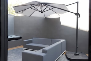 A modern outdoor seating area with a grey sofa and a large umbrella. - 16 de Septiembre by Homi Rent (Santiago de Querétaro)