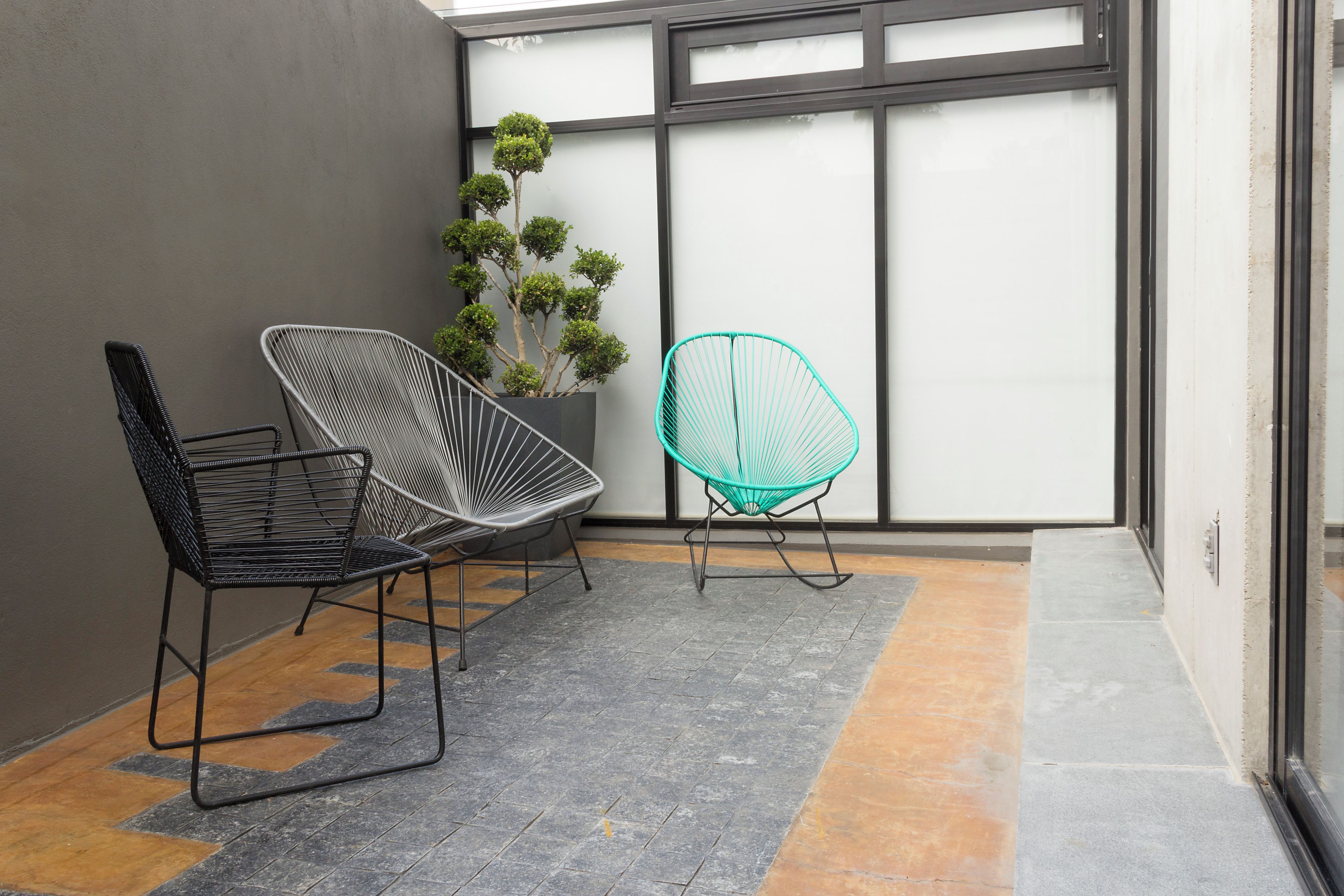 Un interior modern amb dues cadires, una planta en test i una finestra gran.