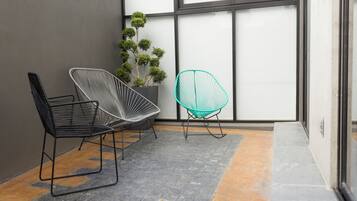 Un interior modern amb dues cadires, una planta en test i una finestra gran.