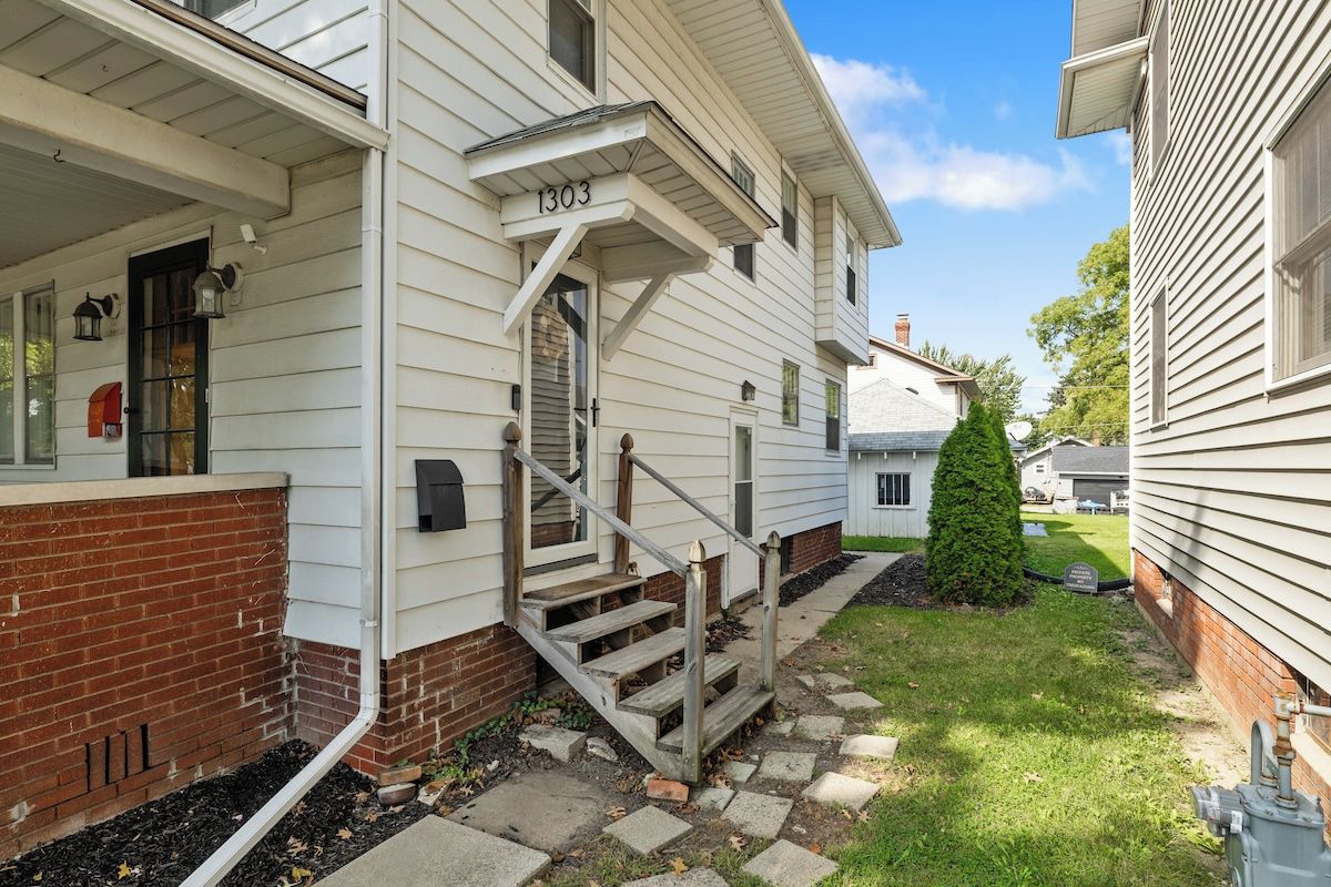 A two-story house with a front porch, a brick foundation, and a mailbox.