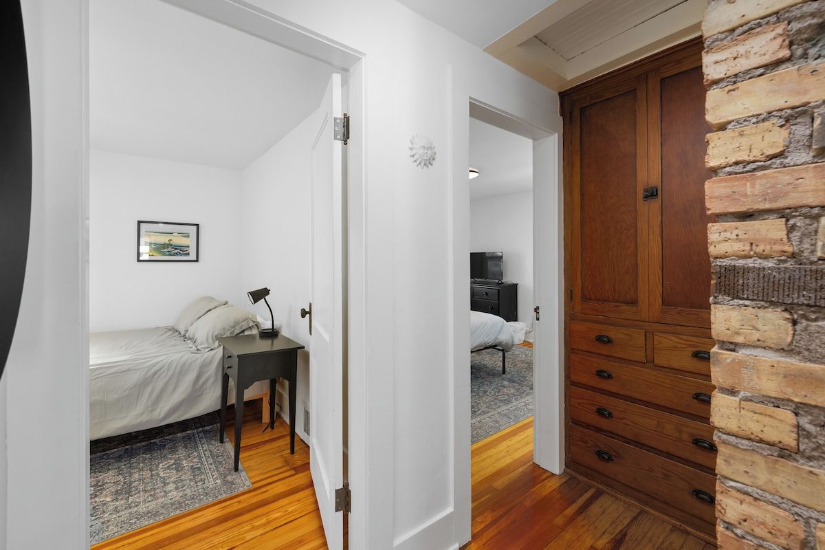 A room with a bed, a desk, a dresser, and a television in the background.