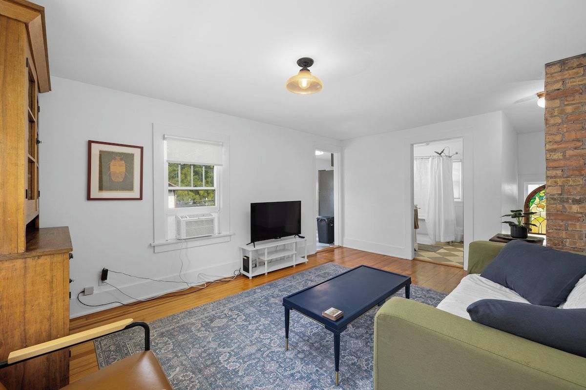 A living room with a television, a coffee table, a sofa, and a patterned rug.