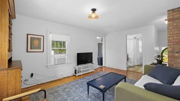 A living room with a television, a coffee table, a sofa, and a patterned rug.
