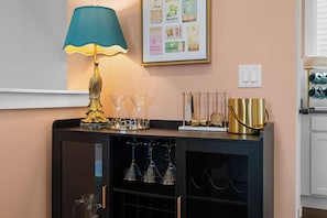 A bar area with a teal lamp, wine glasses, a gold decorative piece, and a framed menu on the wall. - Joey's House – Rooftop, Sauna & Karaoke Stage (Nashville)