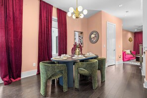 A dining area with a round table, four chairs, and a chandelier. - Joey's House – Rooftop, Sauna & Karaoke Stage (Nashville)