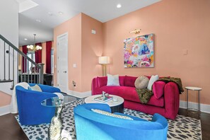 A modern living room with a blue sofa set, a red sofa, and a coffee table. - Joey's House – Rooftop, Sauna & Karaoke Stage (Nashville)