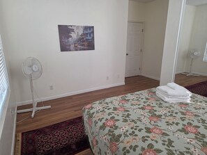 A bedroom with a bed, a standing fan, a door, and a painting on the wall. - Casa Tranquilla in Evergreen, San Jose (San Jose)