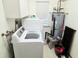 A laundry area with a front-loading washing machine, a dryer, and a water heater.