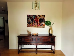 A wooden console table with a decorative elephant figurine, a vase with a plant, and a framed painting above it.