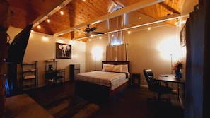 Een gezellige slaapkamer met een bed, een bureau, een stoel en een plafondventilator.